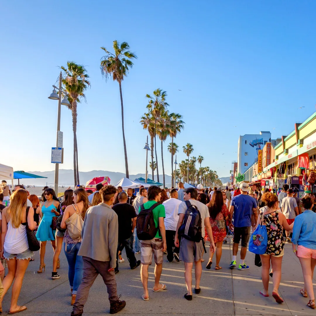 Crowds walking and exploring the Venice Beach boardwalk in Los Angeles on a sunny day