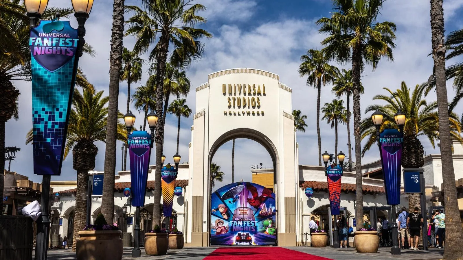 Universal Studios Hollywood entrance arch framed by palm trees and event banners