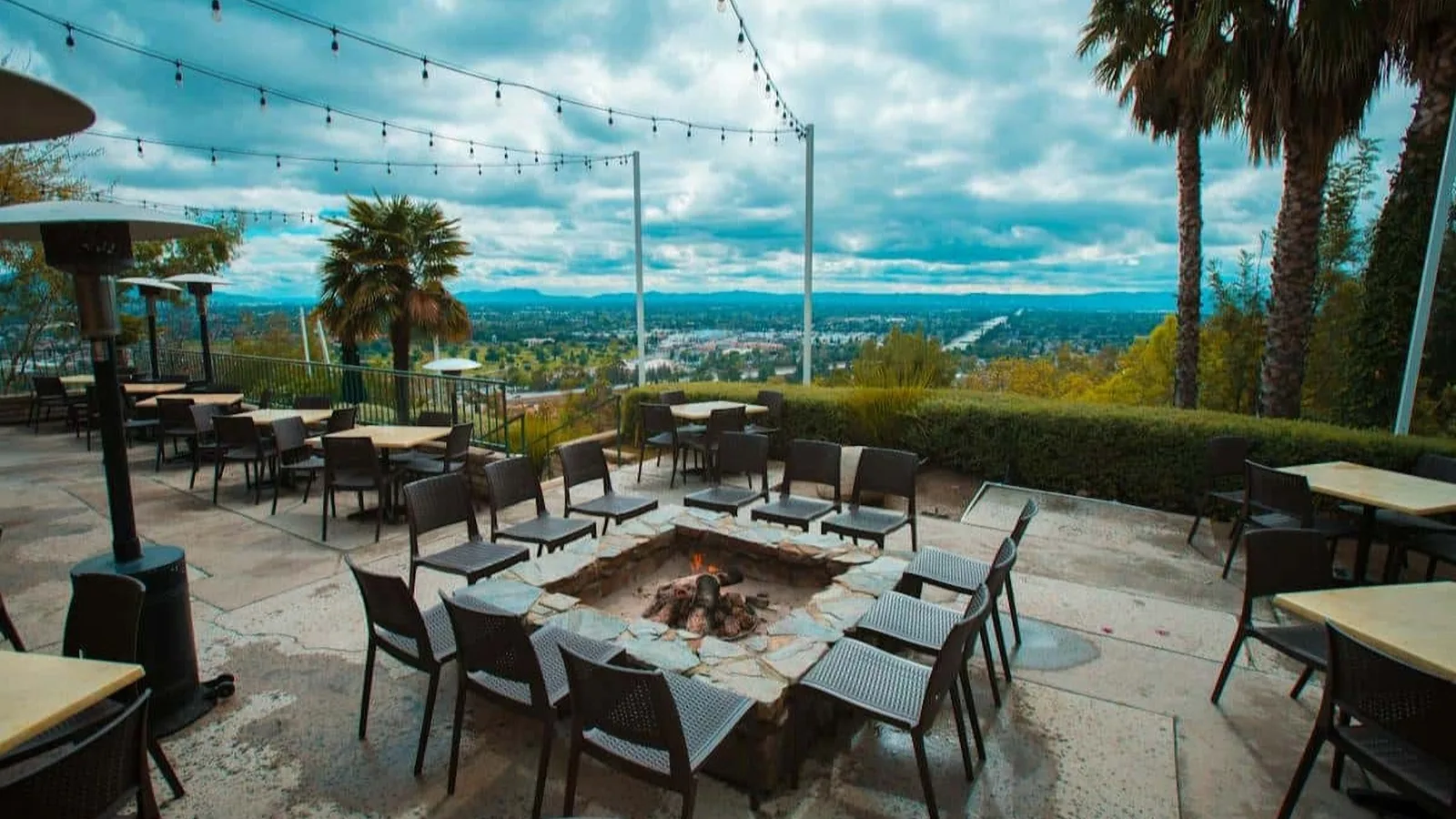 Hilltop patio with a square fire pit, string lights and valley views