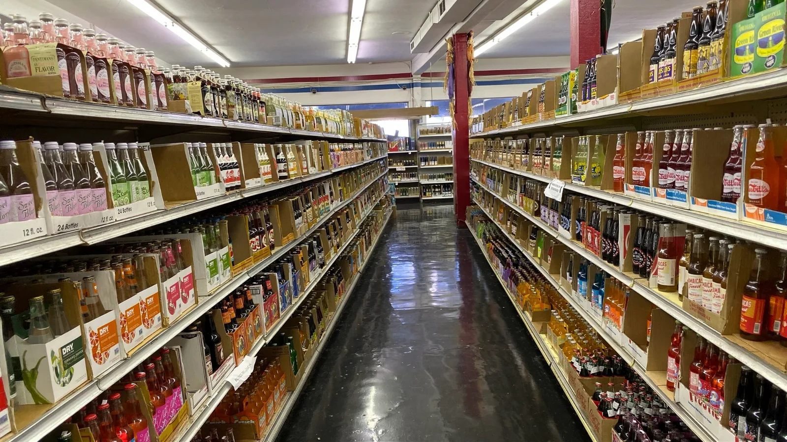 Shop aisle lined with shelves of bottled sodas and speciality drinks