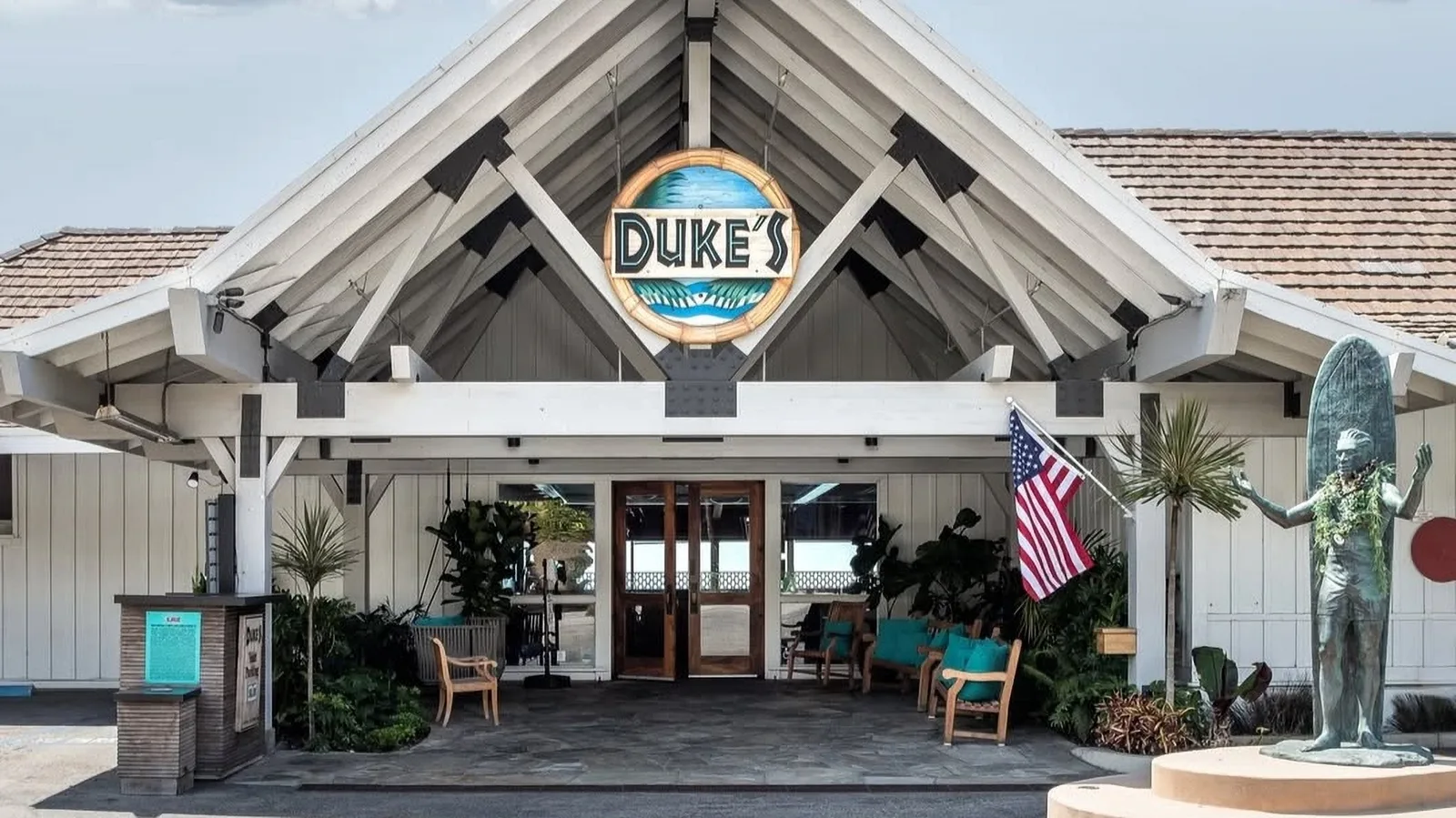 Peaked timber entrance of Duke's restaurant with its logo sign and flag