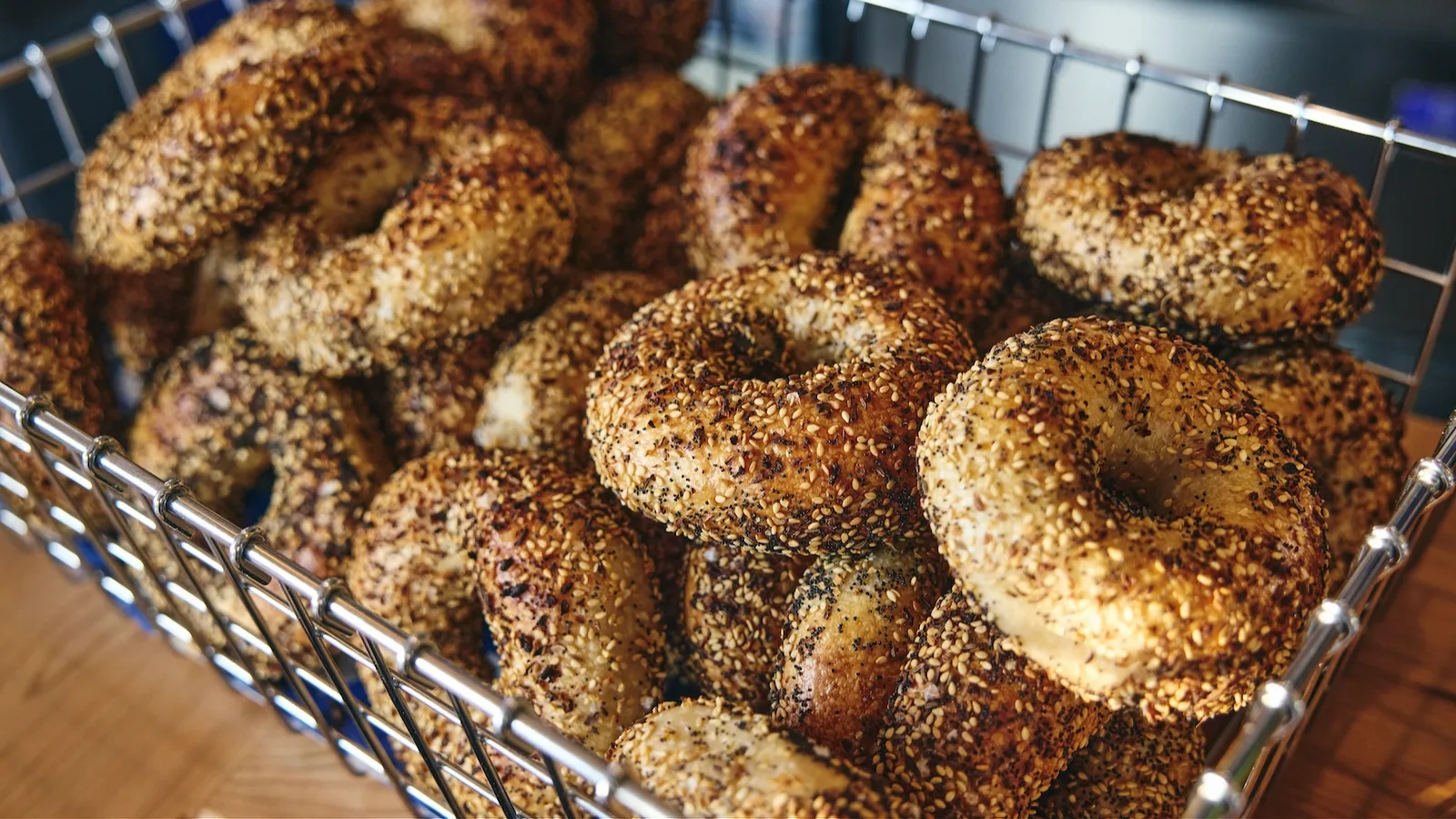 Wire basket piled with freshly baked seeded everything bagels