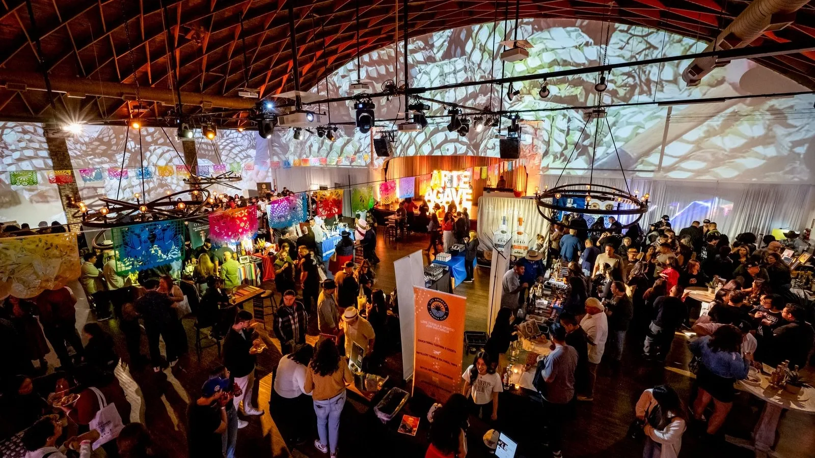 Crowds fill a vaulted market hall hung with papel picado banners