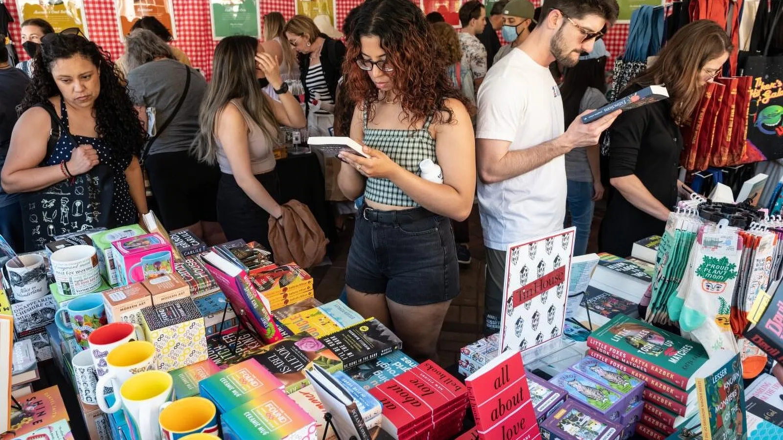 Visitors browse paperbacks and mugs at an outdoor book festival stall