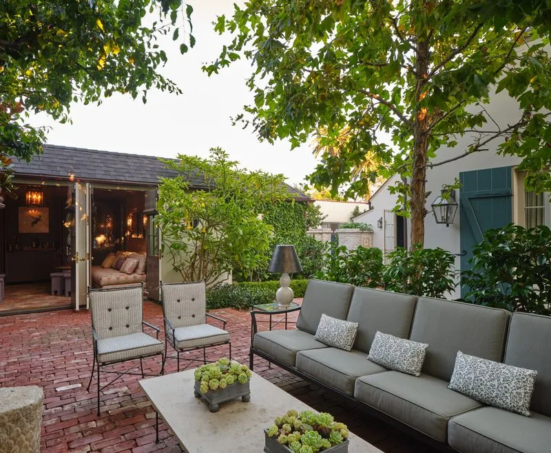 Garden courtyard with a cushioned sofa, brick paving and dense greenery