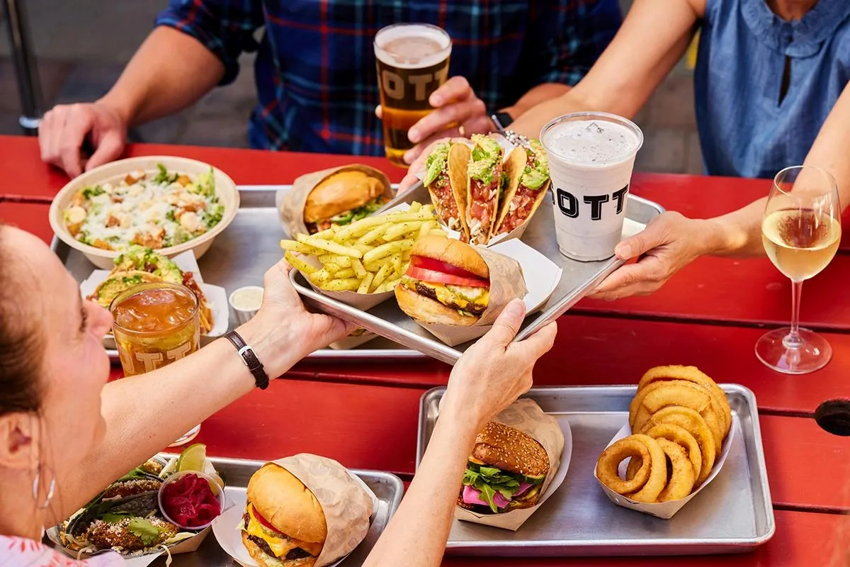Trays of burgers, tacos, fries and onion rings on the patio at Gott's Roadside
