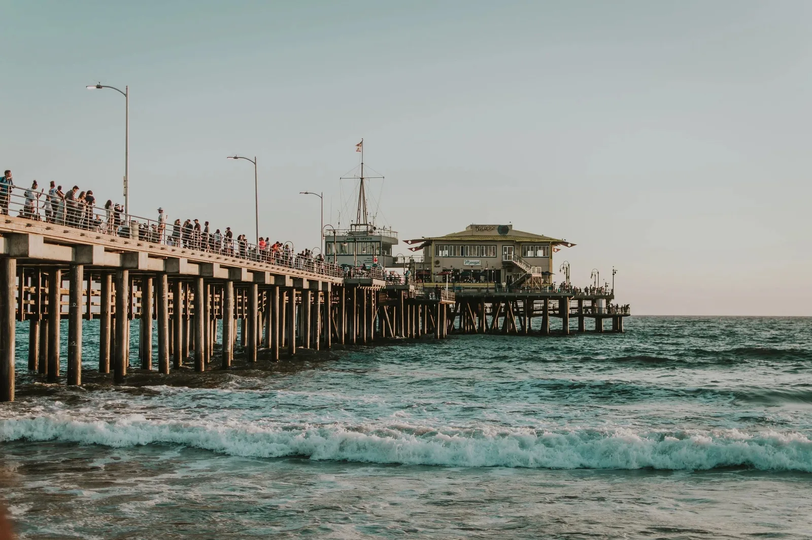 Wooden pier on pilings with crowds above breaking waves