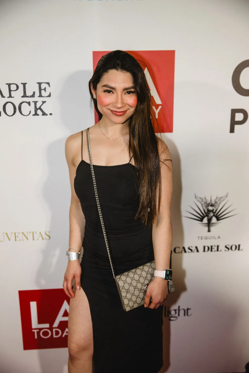 A guest in a black slip dress carries a chain shoulder bag