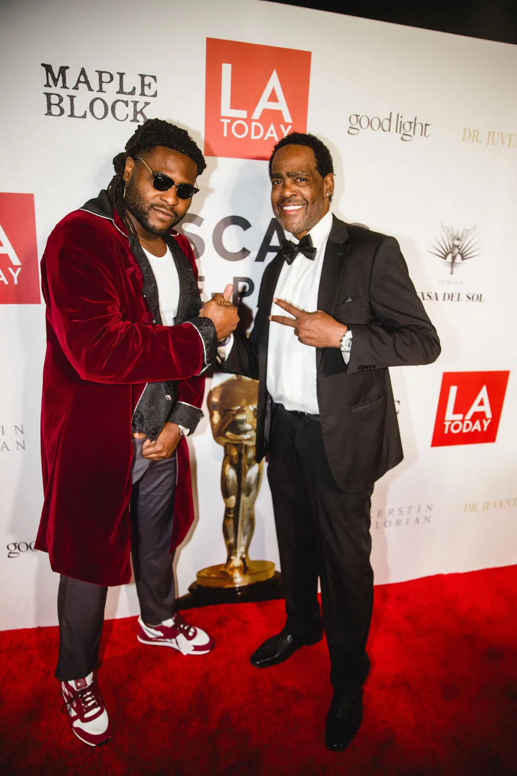 Two guests joke together, one in red velvet, one in a tuxedo