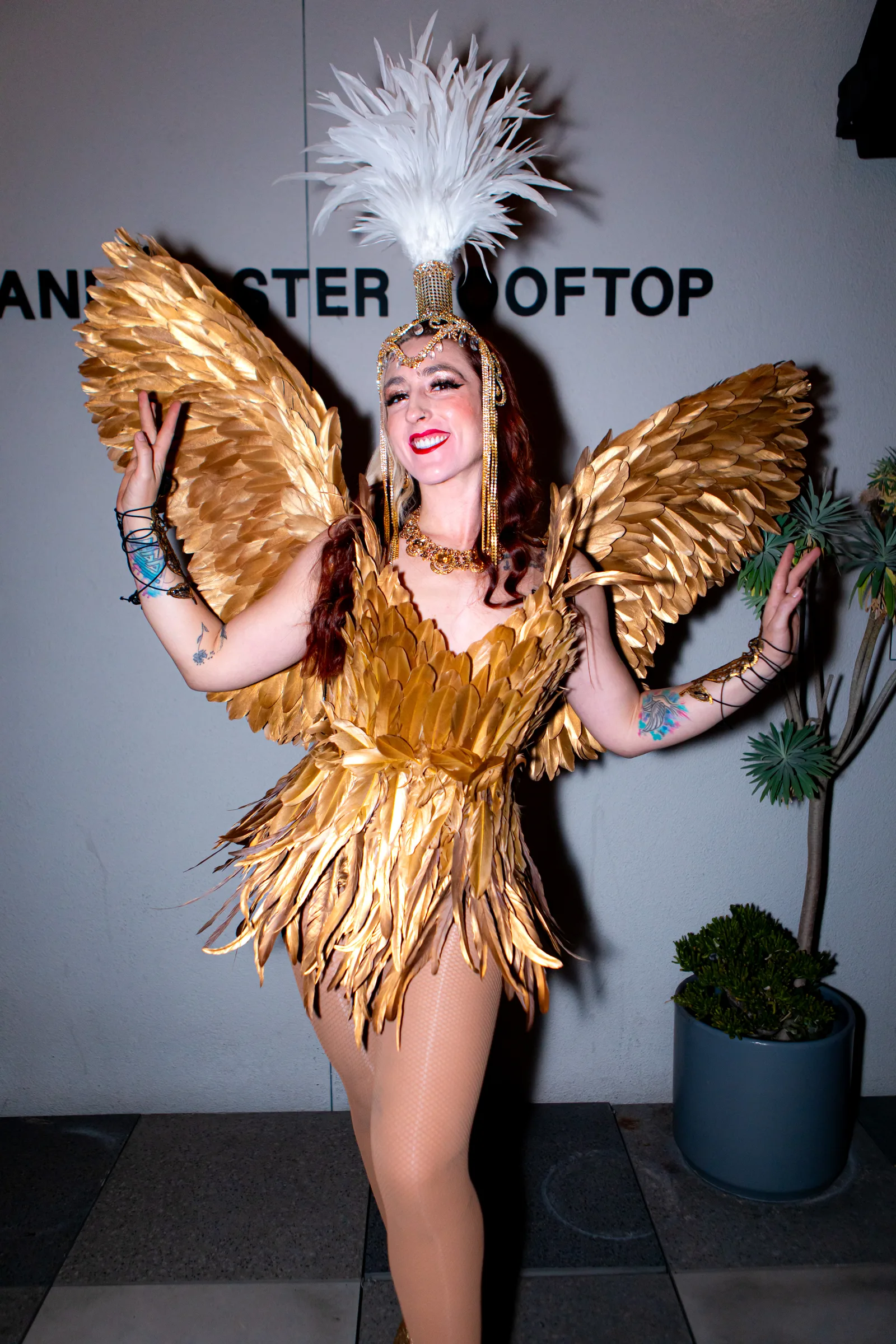 A performer poses in a gold feathered costume with large wings