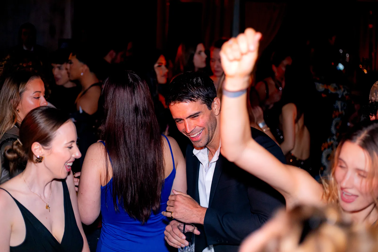 Guests dance closely together in a crowded dim room