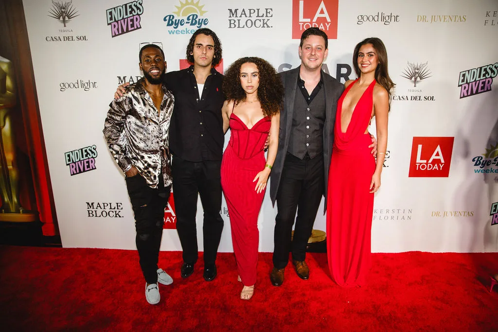 Five guests in formal wear line up on the red carpet