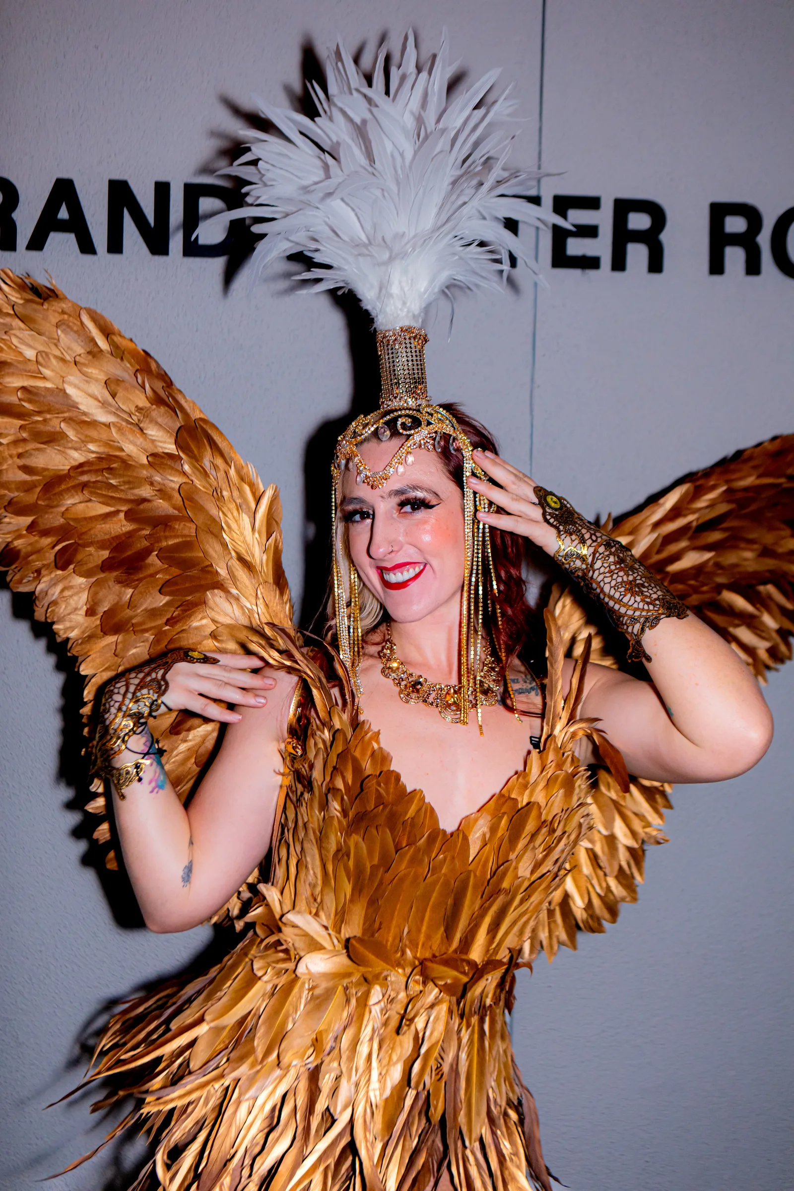 A performer in a gold feathered costume with wings and jeweled headpiece