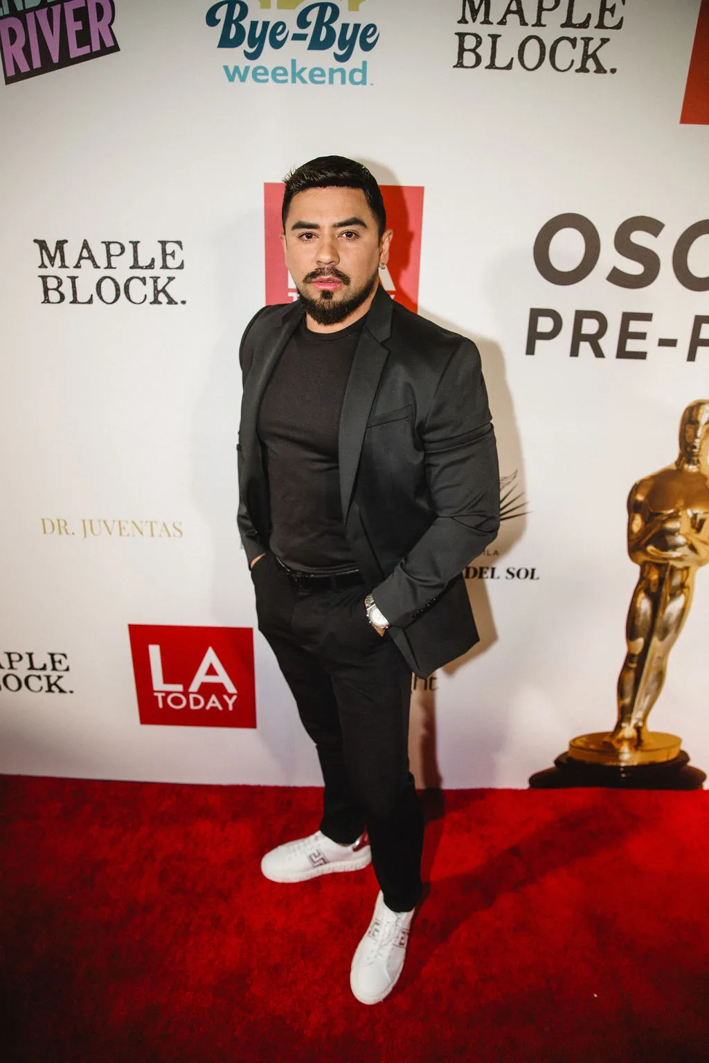 A guest in an all-black suit poses with hands in pockets