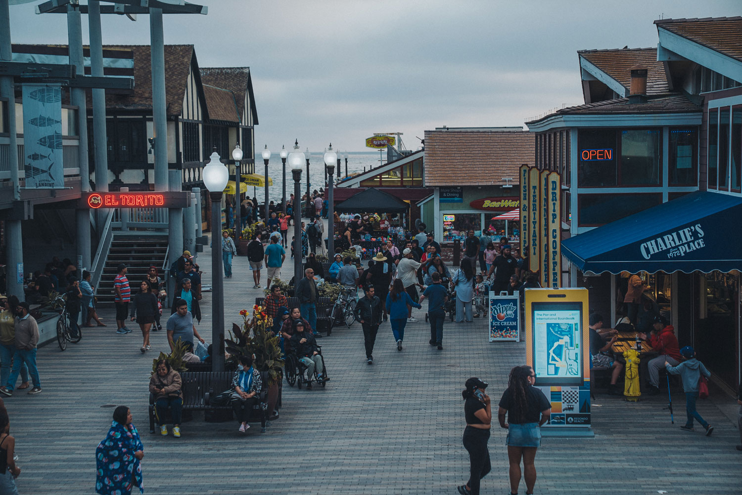 The Redondo Beach Pier boardwalk lined with shops and restaurants at dusk.