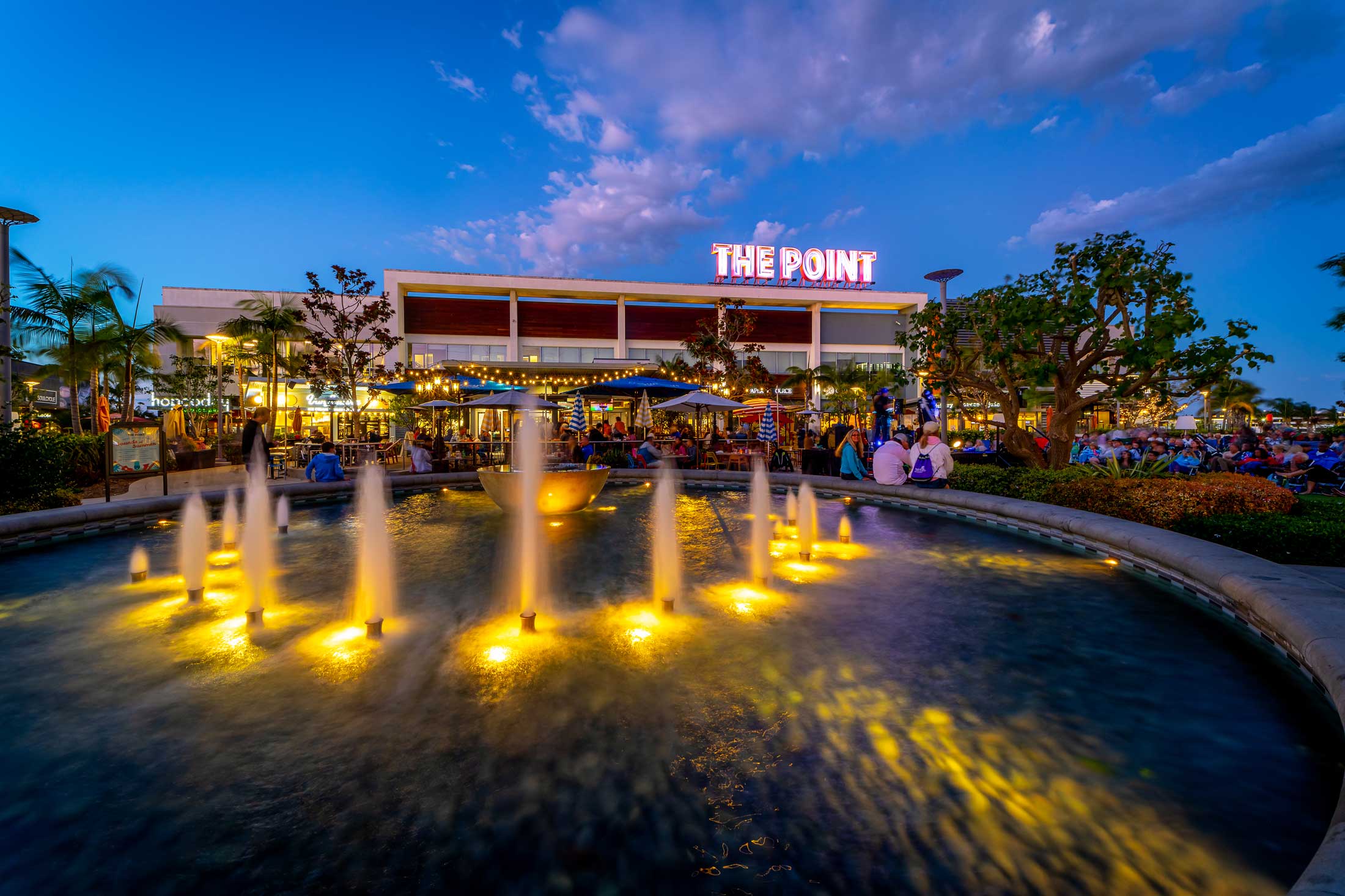 The Point shopping center's lit-up sign at dusk in El Segundo, with its central fountain.