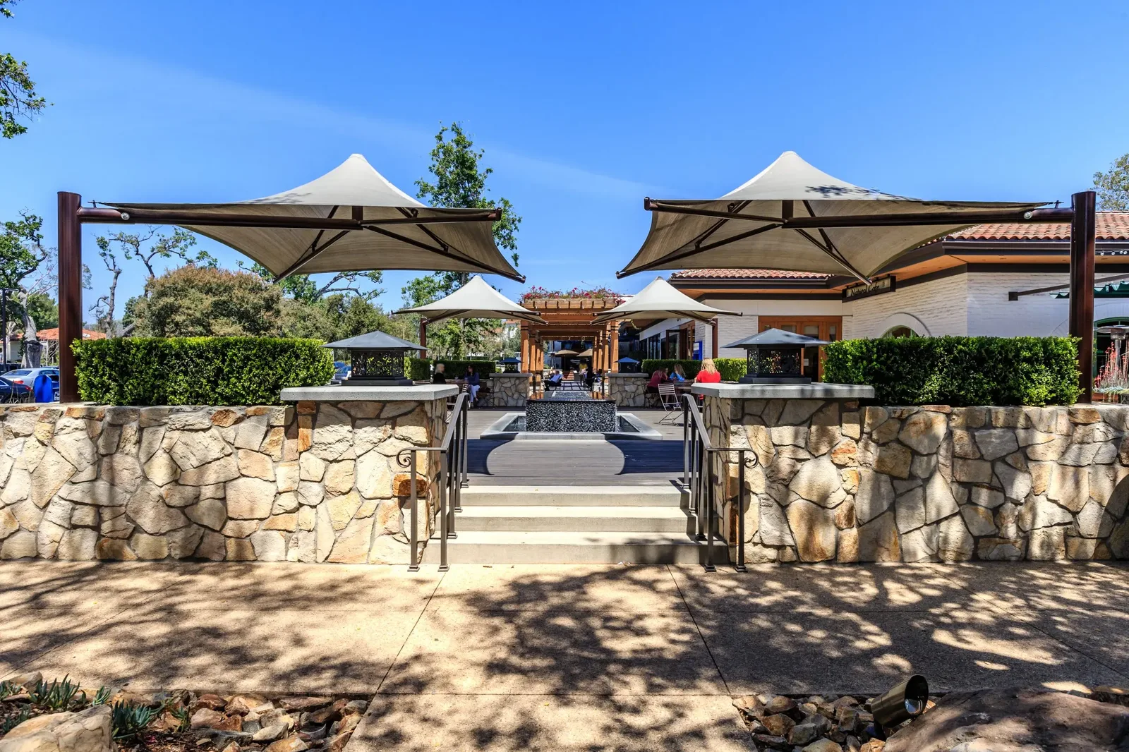 Shaded outdoor seating and a fountain plaza at The Village shopping center in Walnut.