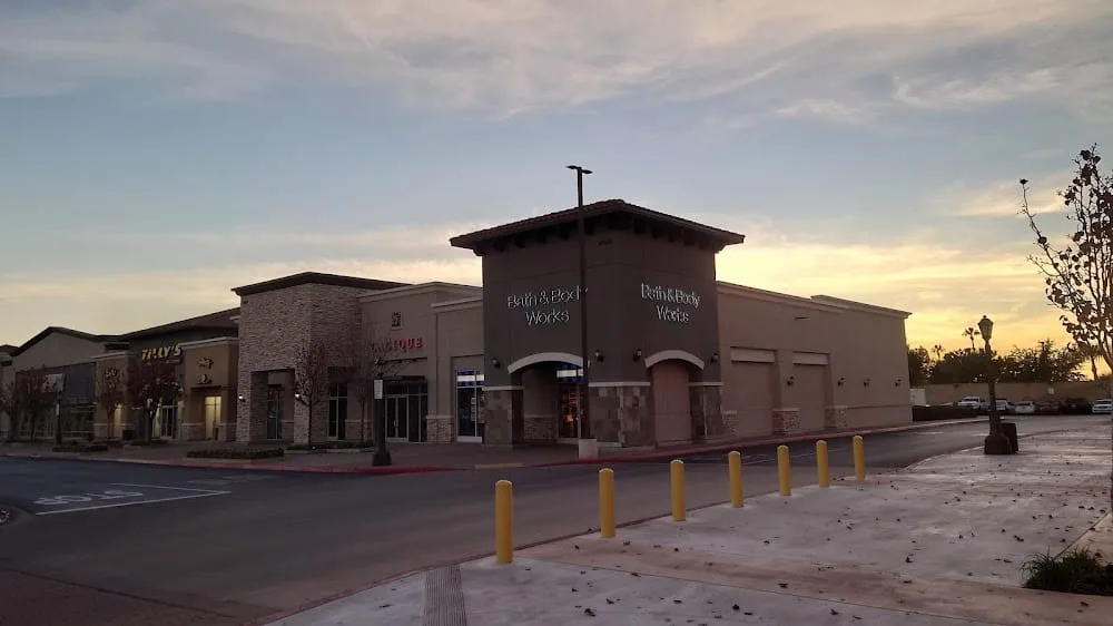 Beige stucco retail block at dusk with an empty street and yellow bollards