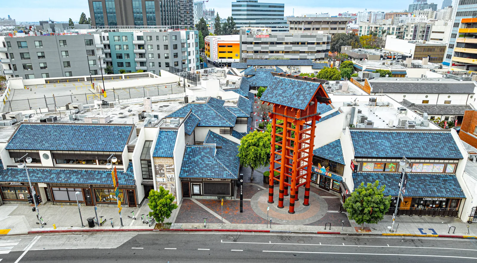 Aerial of blue tiled roofs and a red wooden tower, high rises behind