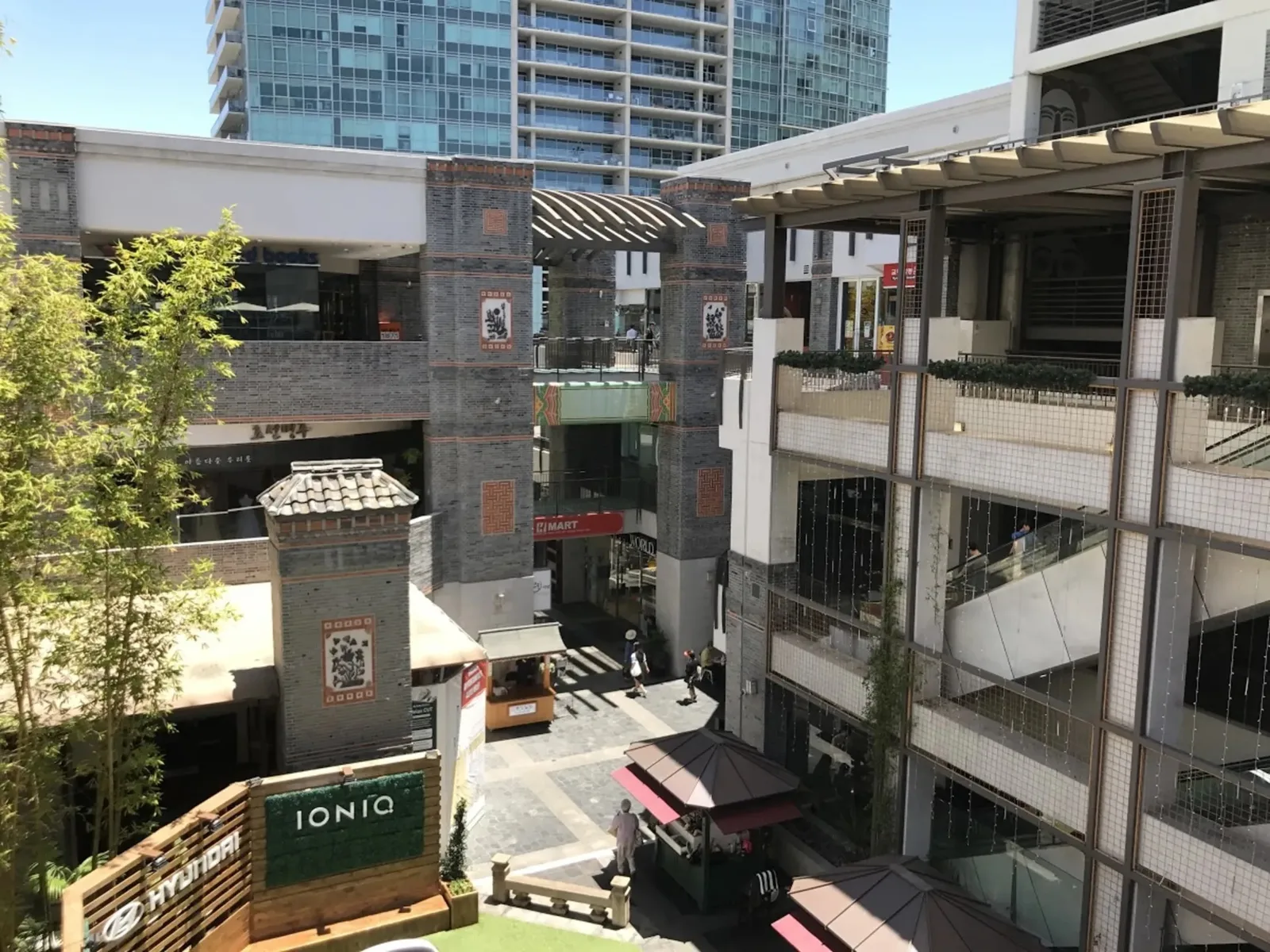Concrete and glass retail complex with signage and a high rise tower behind