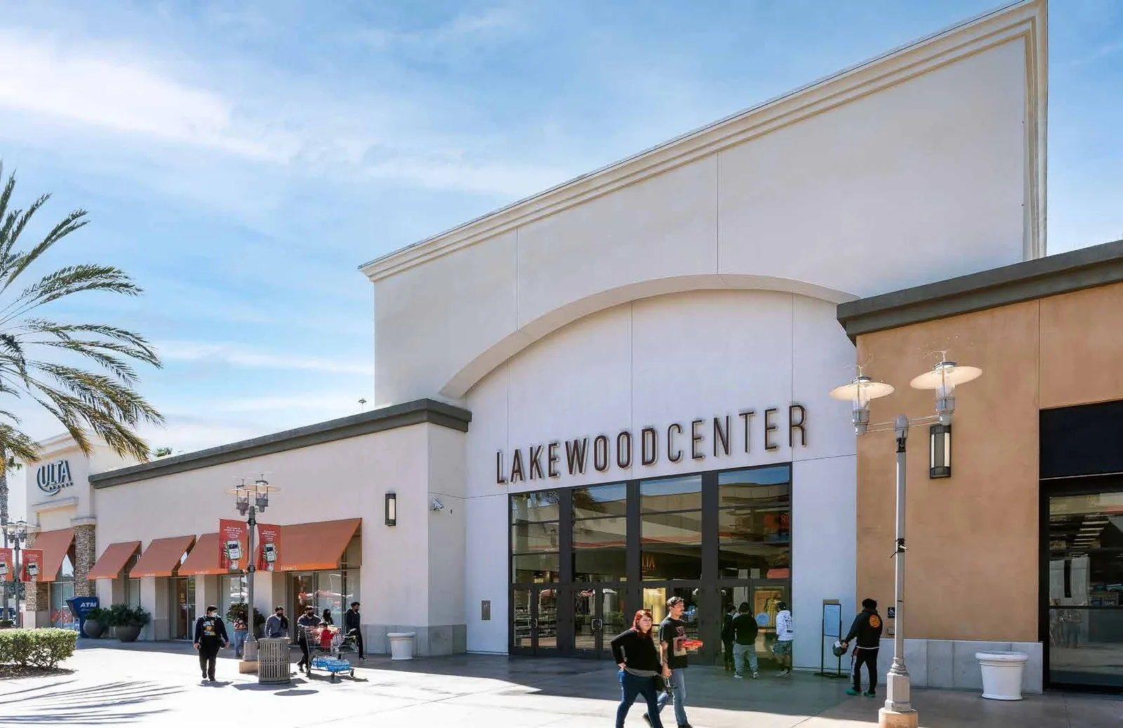 LAKEWOOD CENTER entrance in white stucco with shoppers near the glass doors