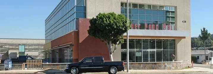 Blank stucco and glass mall corner with a pickup truck parked at the curb