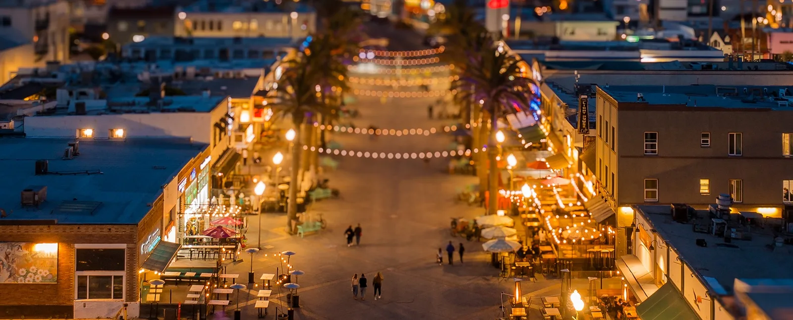Lit restaurant patios along the pier plaza at night