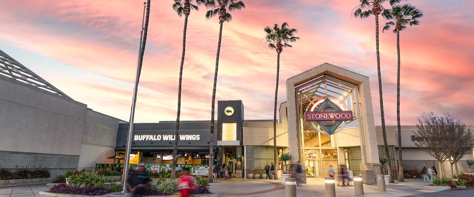 Mall exterior at sunset, pink sky over palms and a Buffalo Wild Wings