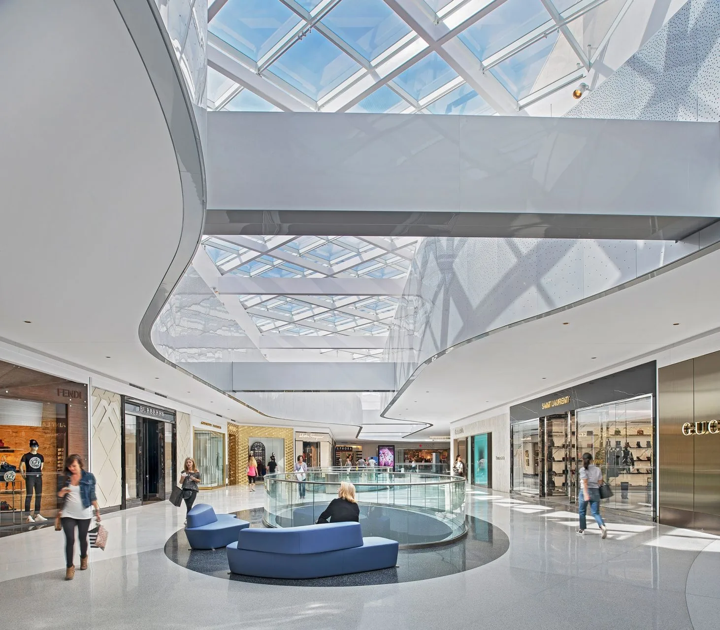 Bright white mall interior with an angular glass skylight and curved balcony