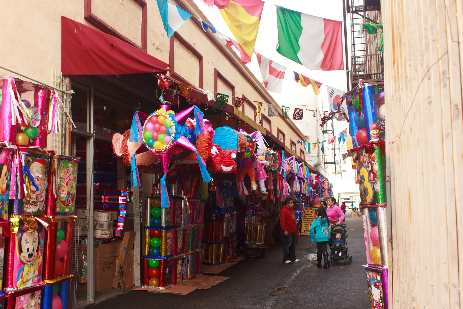 Sidewalk stalls crammed with pinatas, toys and balloons under a red awning
