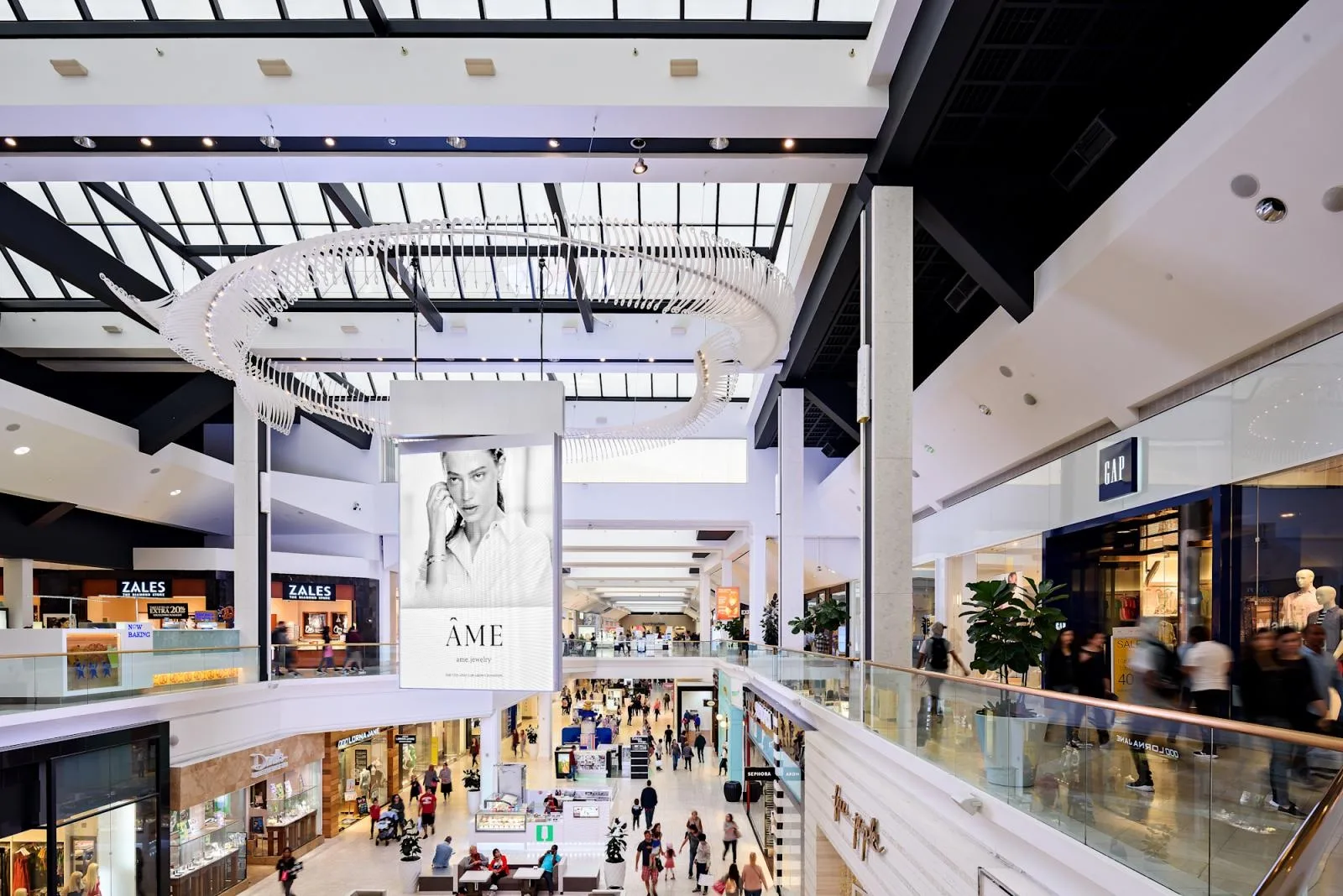 Enclosed mall with a white ribbed ceiling and shoppers on the level below