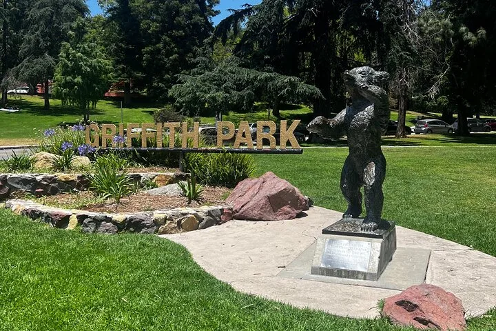 Bear statue on a plinth in a park beside large park letters
