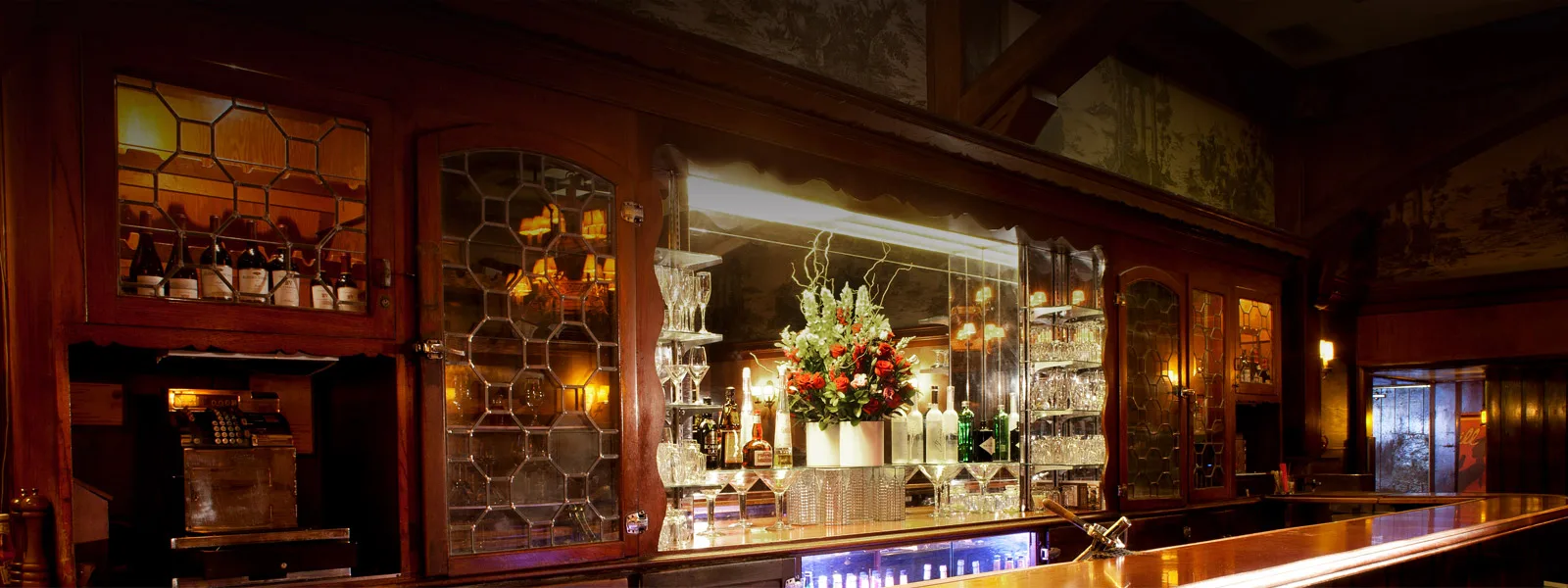 Ornate back bar with mirrors, bottles and a tall flower arrangement