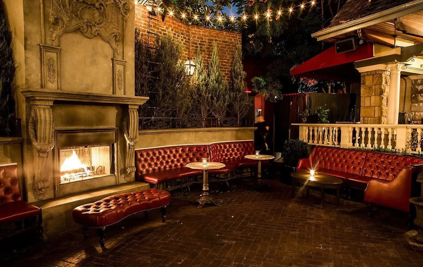 Vintage lounge with a lit fireplace, red tufted banquettes and ivy walls