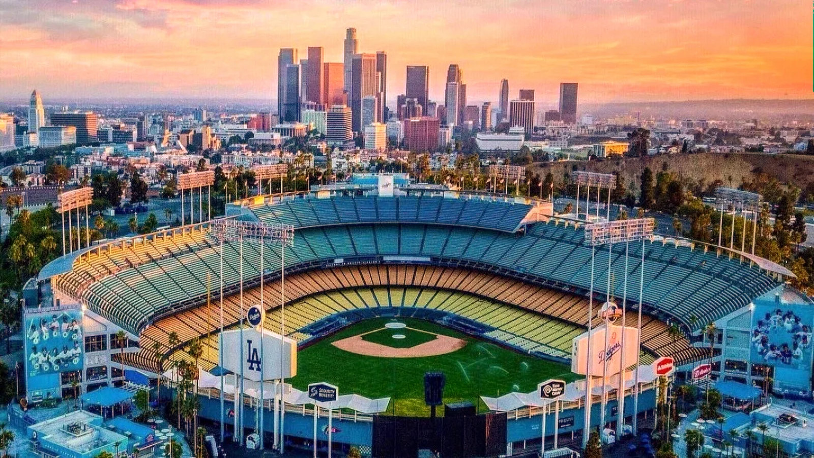 Aerial view of Dodger Stadium at sunset overlooking the Downtown LA skyline.
