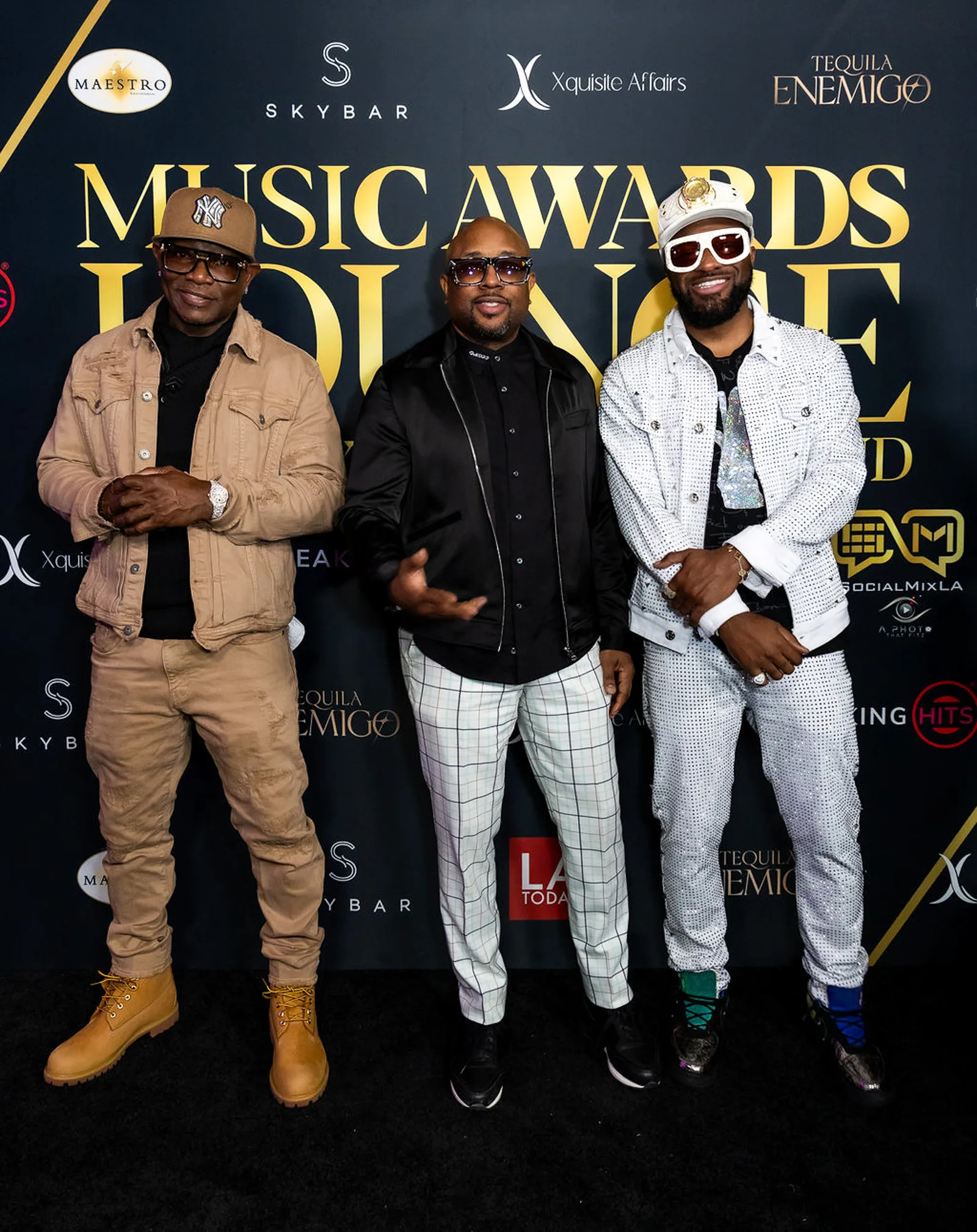 Three guests in casual jackets and jeans pose at the backdrop