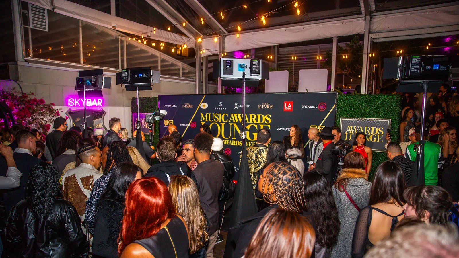 A beautifully dressed crowd poses on the red carpet for paparazzi and media at LA Today's Grammys Pre-Party at Skybar Los Angeles.