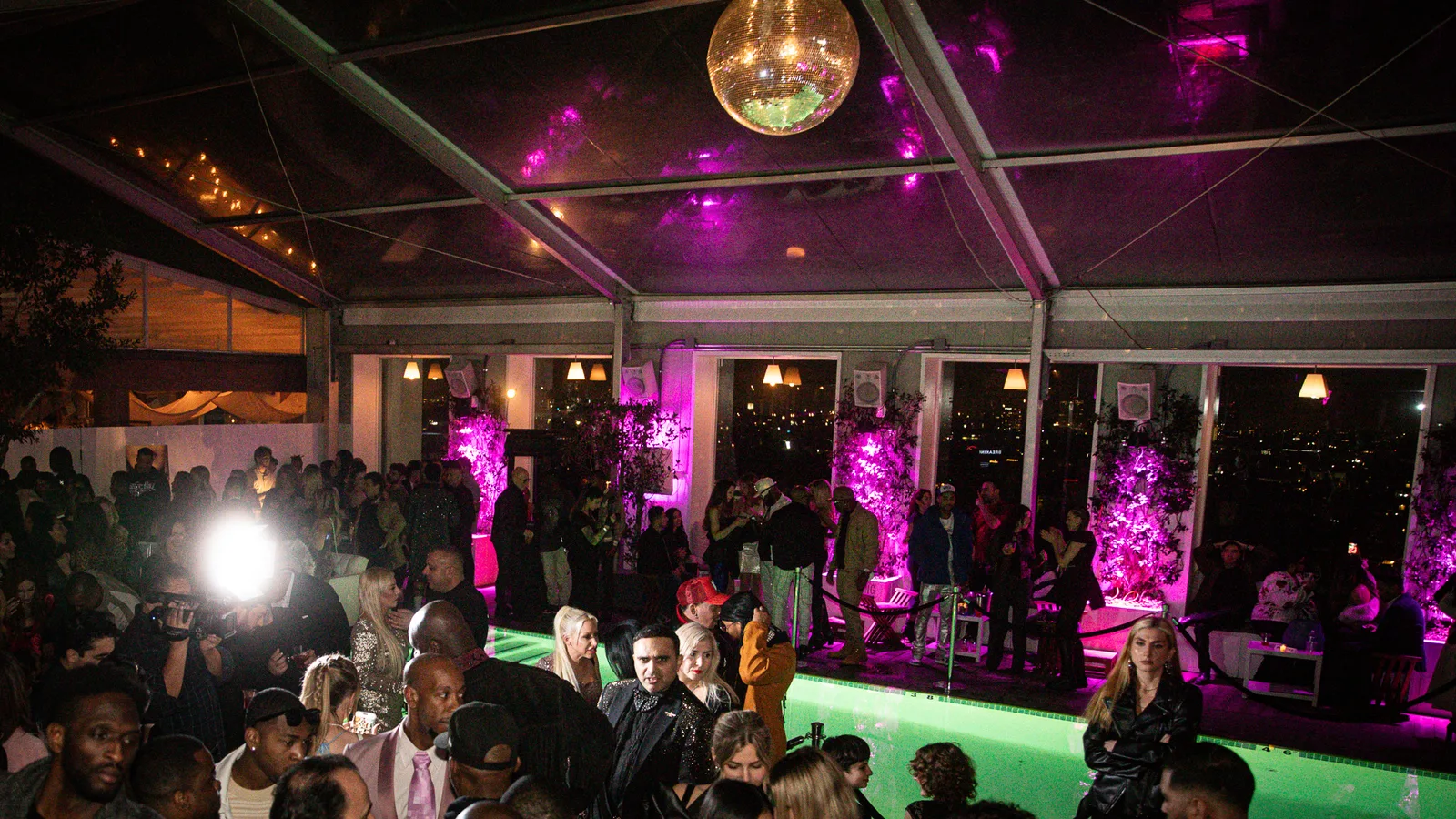Wide view of a rooftop party tent with a disco ball and pink lighting