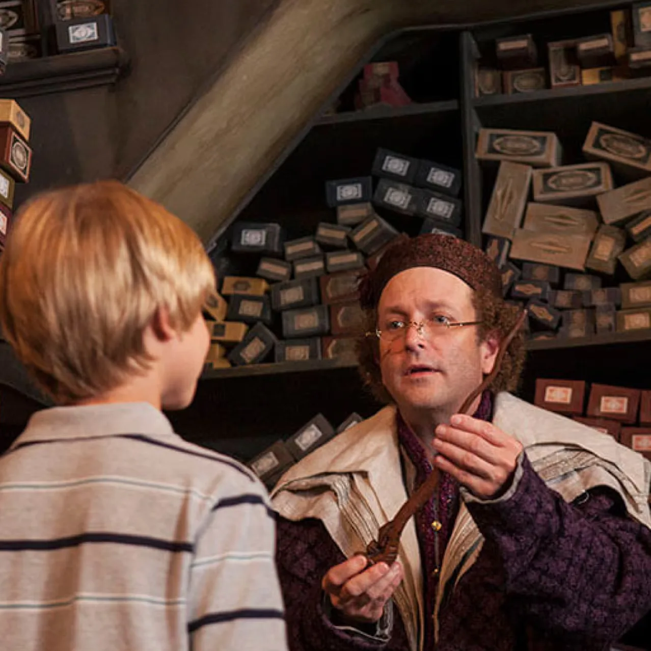 Boy and a shopkeeper facing each other inside a small wand shop
