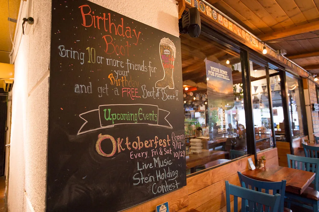 Chalkboard sign listing Oktoberfest events on a covered restaurant patio