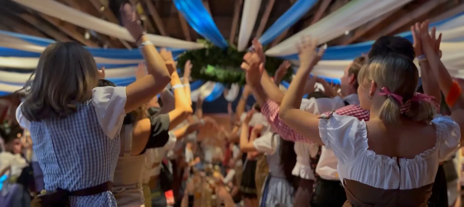 Crowd in traditional dress raising arms under hanging streamers
