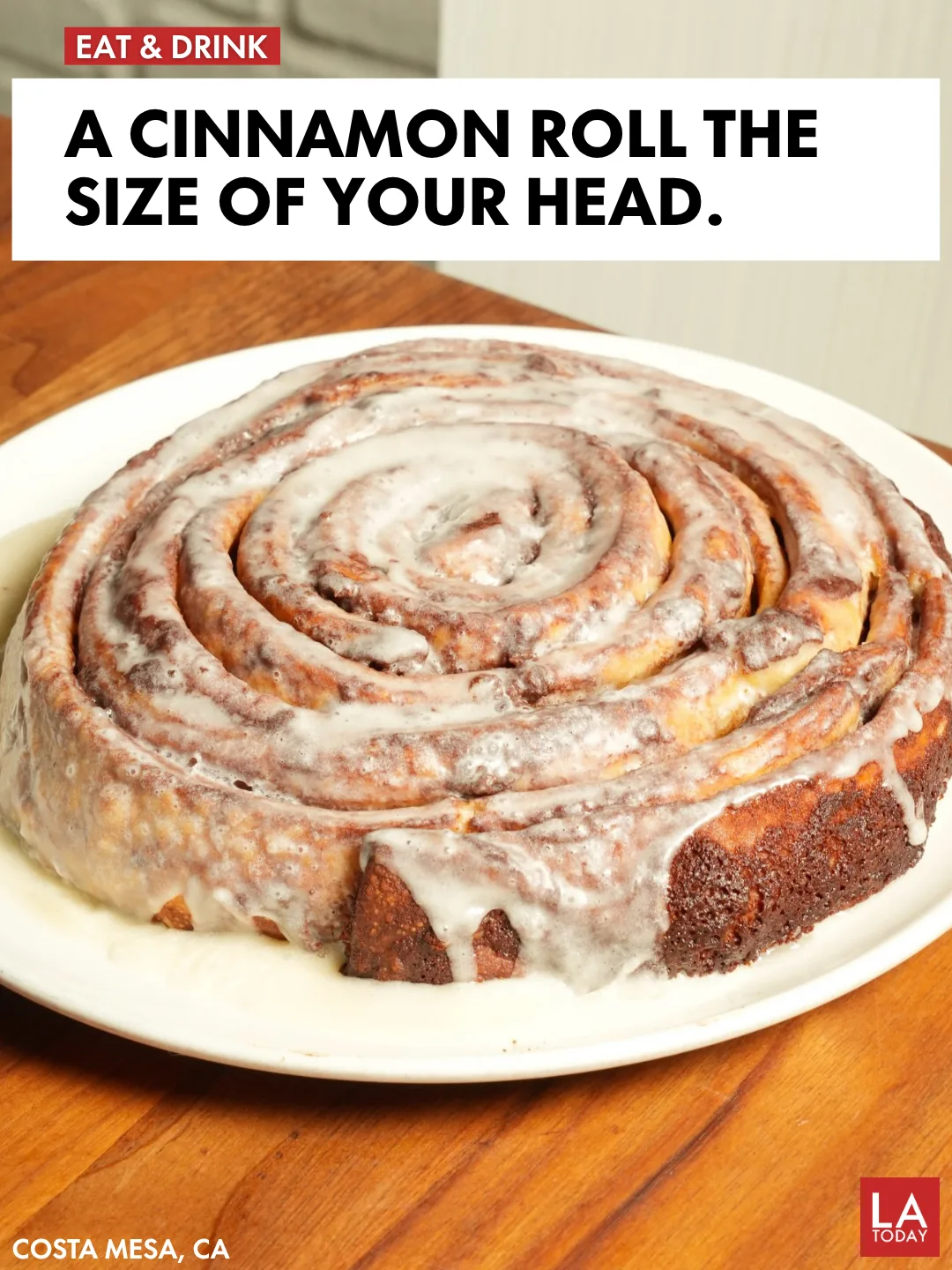 The Giant Cinnamon Roll at Plums Cafe in Costa Mesa, iced and filling an entire plate