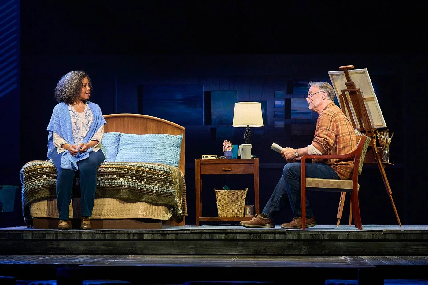 Two actors on a lit living room set onstage