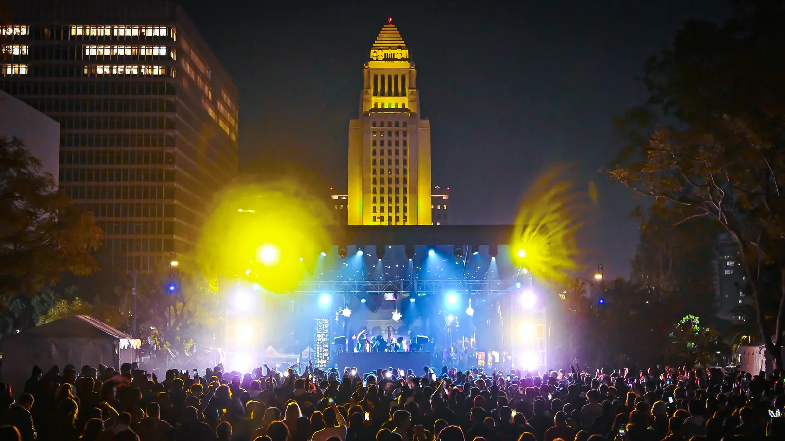 Crowd dancing at Gloria Molina Grand Park's NYELA concert with bright stage lights